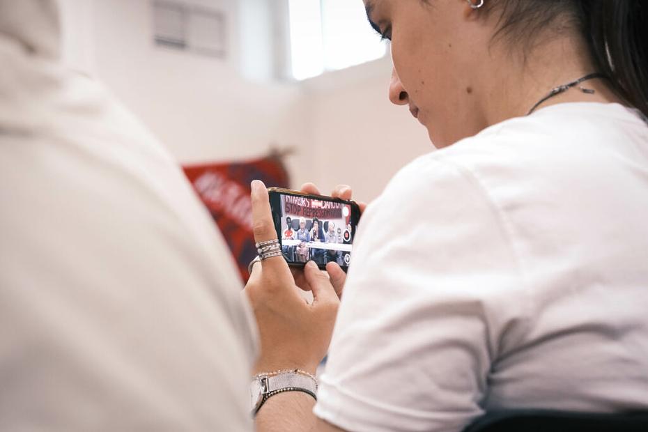 Une journaliste filme les intervenants à l'aide de son smartphone. 